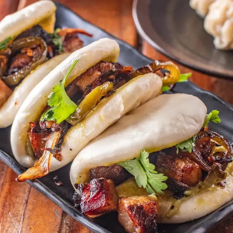 Pork belly bao buns on black plate