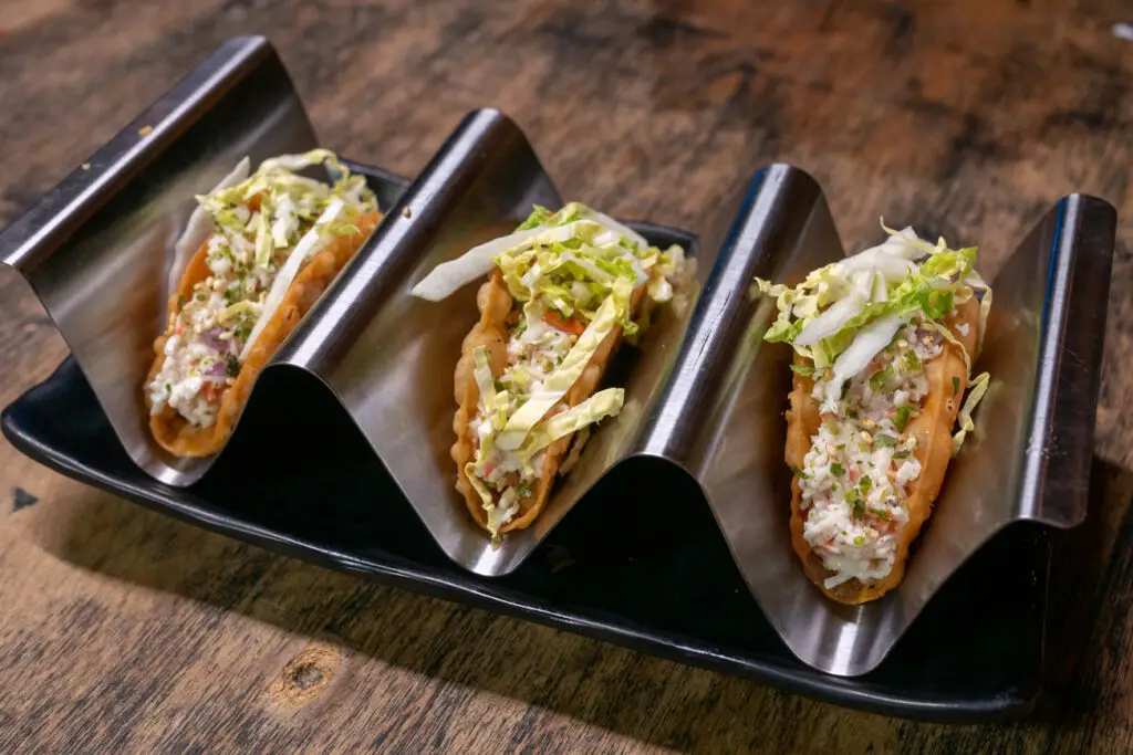 a row of tacos on a black tray