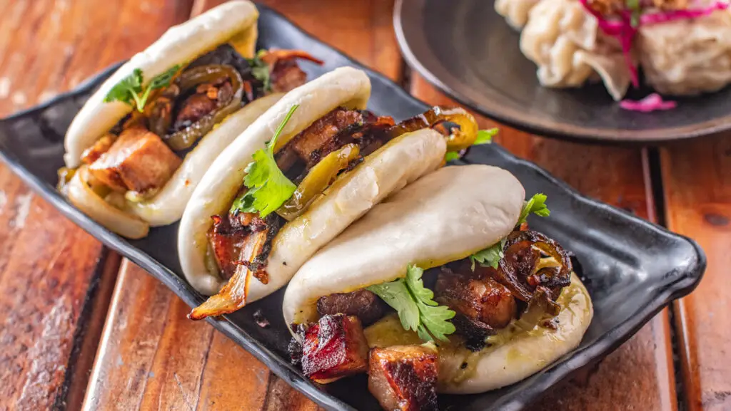 a plate of pork bao buns on a table