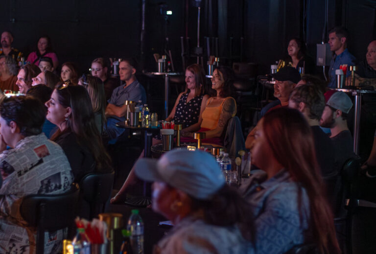 a group of people sitting in chairs watching comedy in denver