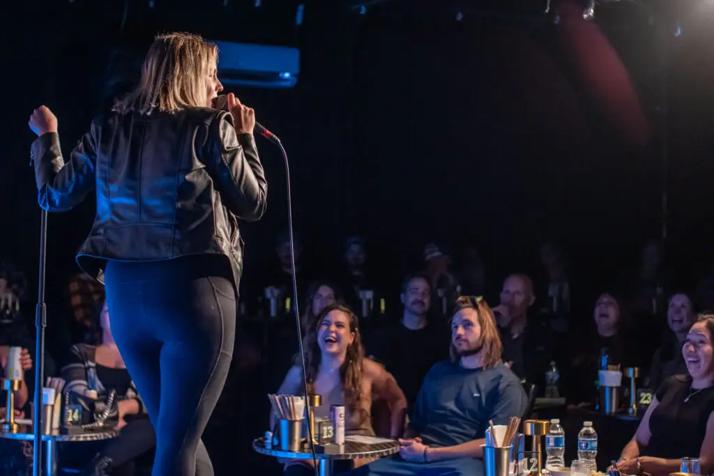 a woman doing stand up comedy into a microphone at one of our comedy shows.